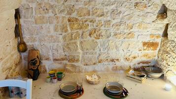 Pared de piedra con un montaje rústico para comer, que incluye platos, cuencos y una cuchara de madera.