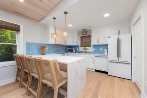 A modern kitchen with a large island, white cabinetry, and a built-in microwave. - 2 Private Living Spaces, 2 Hot Tubs and Bikes! (Kill Devil Hills)