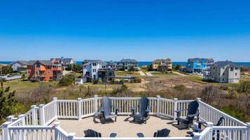 A coastal residential area with a view of the ocean, featuring houses with various architectural styles and a deck with chairs.