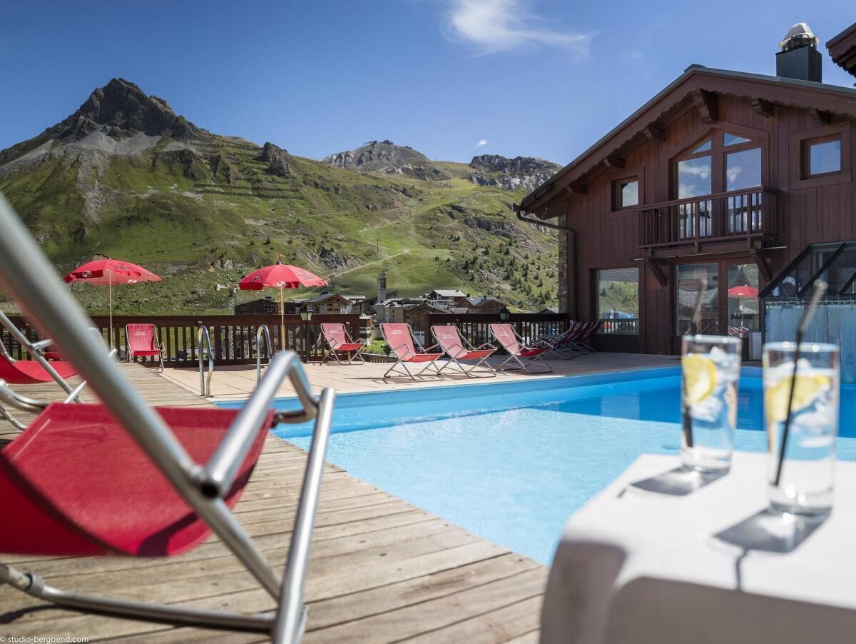 A pool area with lounge chairs and umbrellas, overlooking a mountain.