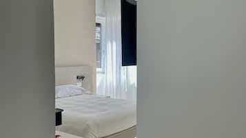 Een moderne hotelkamer met een bed, een nachtkastje en een klein houten bijzettafeltje.