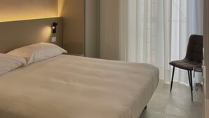 Una habitación de hotel moderna con una cama grande, una silla y un armario.
