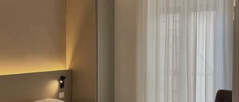 Una habitación de hotel moderna con una cama grande, una silla y un armario.