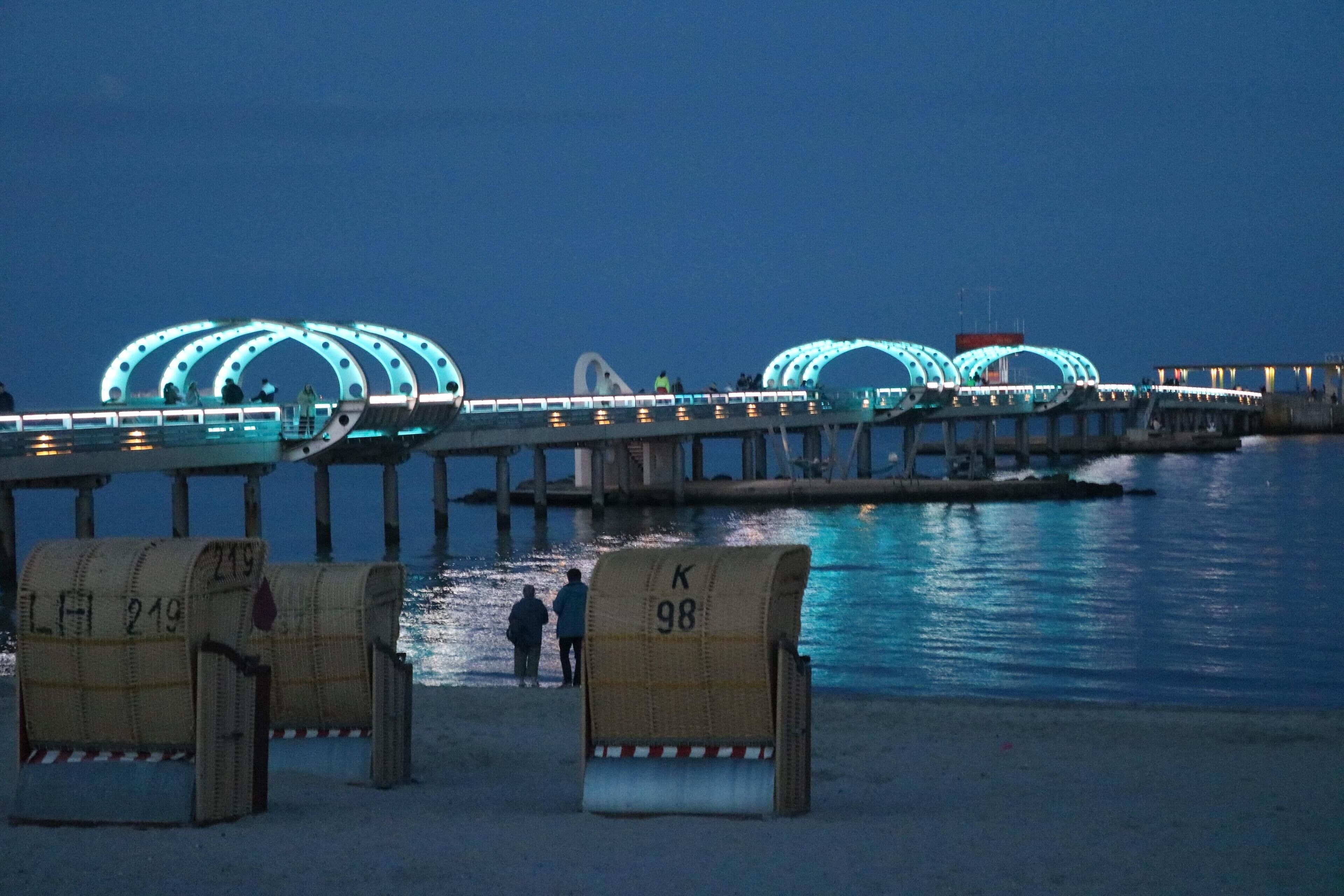 A bridge with illuminated arches over a body of water.