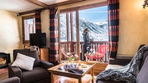 Un salon chaleureux avec une cheminée, un téléviseur et une vue sur une montagne enneigée.