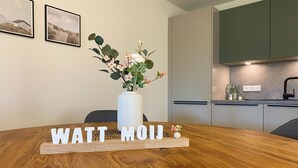 Una mesa de madera redonda con un jarrón blanco de flores y un cartel de madera que dice