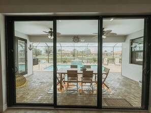 A patio with a pool, dining table, chairs, and ceiling fans. - Family home in Cape Coral (Cape Coral)