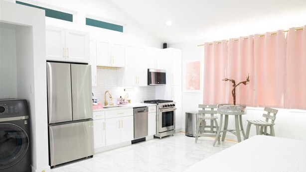 A modern kitchen with white cabinets, stainless steel appliances, a microwave, and a dining area with a table and chairs.