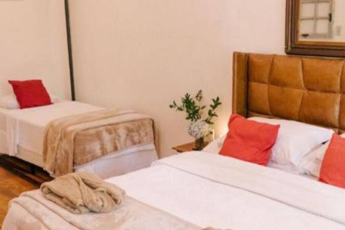 Une chambre d’hôtel avec deux lits, une tête de lit en bois et une petite table sur laquelle est posé un vase de fleurs.