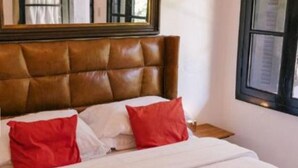 A bed with a brown headboard, white bedding, and red pillows. - Parador Hampel (Sao Francisco de Paula)