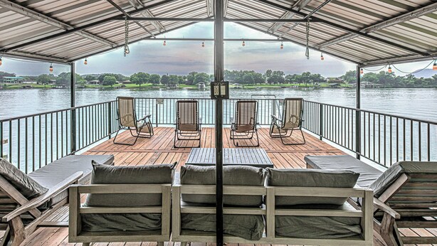 A covered deck with wooden lounge chairs and a view of a lake. - Lakefront 6BR | Ramp, Dock, Views | Sleeps 12 (Kingsland)