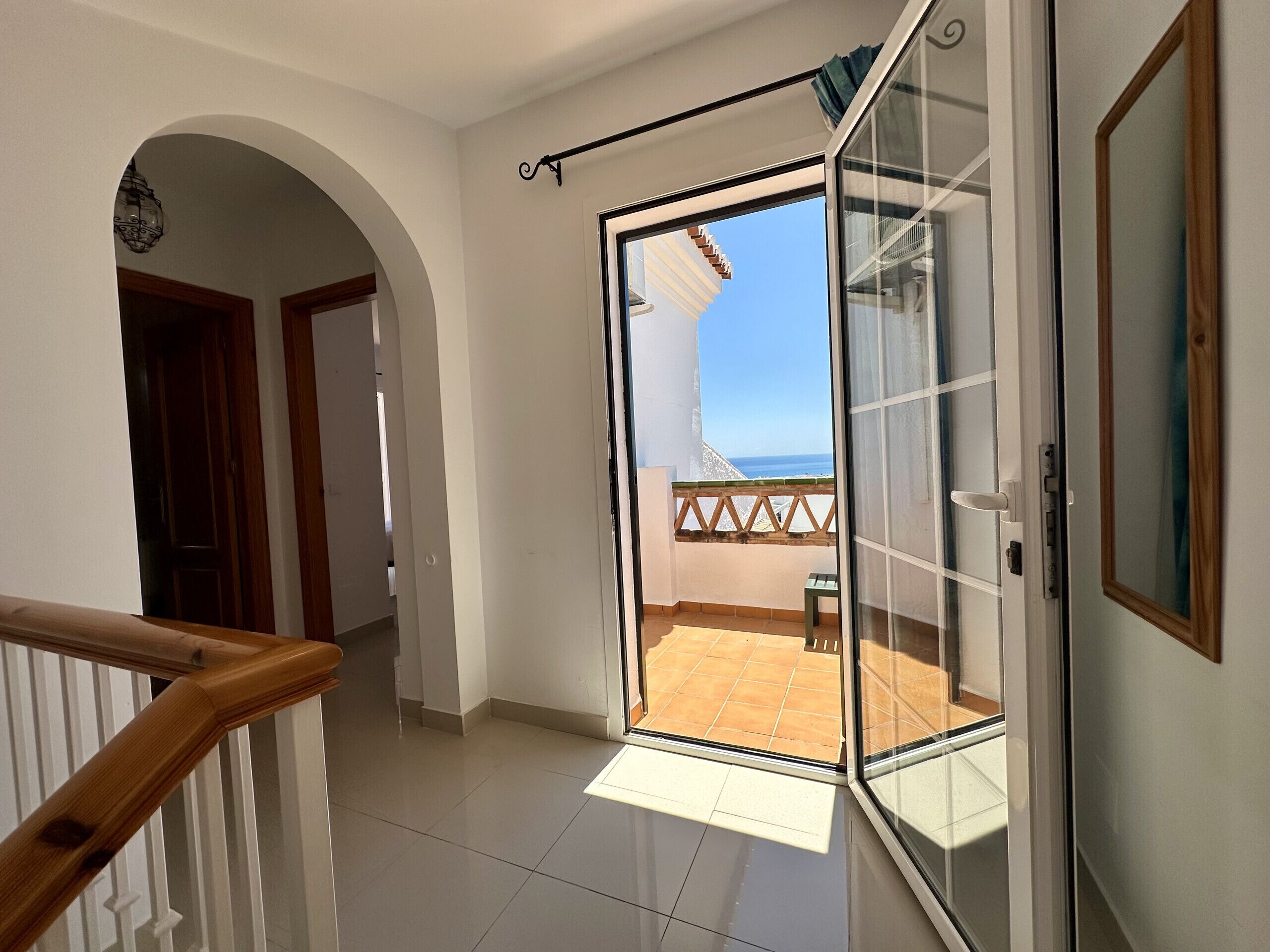 Ein Flur, der zu einem Balkon mit Meerblick führt.