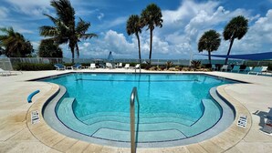 A swimming pool with a curved edge, surrounded by lounge chairs and palm trees. - Adventure Included, Water views, Bikes & Kayak (Jensen Beach)