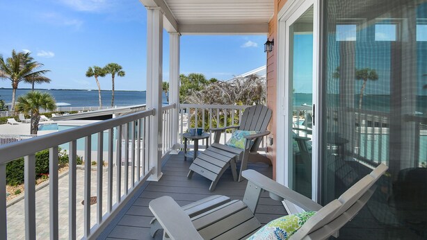 A balcony with two lounge chairs, a small table, and a view of the ocean. - Adventure Included, Water views, Bikes & Kayak (Jensen Beach)