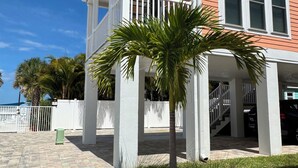 A two-story house with a covered porch, a small palm tree, and a gated driveway. - Adventure Included, Water views, Bikes & Kayak (Jensen Beach)