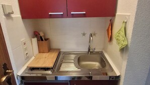 A compact kitchen with a sink, wooden cutting board, and a green towel hanging on the wall. - Beautiful vacation apartment in Himmelberg for a vacation. (Thalfang)