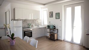 A modern kitchen with white cabinets, a marble backsplash, and a dining area with a wooden table and chairs. - Tenuta Coppola -Cozy Holiday Home between the Amalfi and Sorrento Coasts (Gragnano)