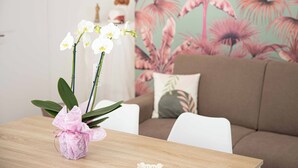 A wooden table with a pink orchid vase, a brown sofa, and a floral-patterned wall in the background. - Tenuta Coppola -Cozy Holiday Home between the Amalfi and Sorrento Coasts (Gragnano)
