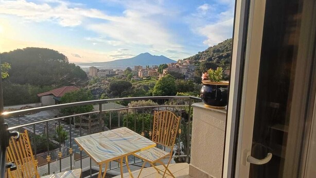 A balcony with a table and chairs, offering a view of a cityscape and a mountain. - Tenuta Coppola -Cozy Holiday Home between the Amalfi and Sorrento Coasts (Gragnano)