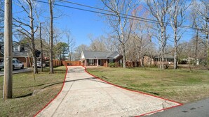 A residential driveway leading to a house with a garage, surrounded by trees and a clear sky. - Charming 3-bedroom Home in Monroe with a Pool Table and Fire Pit, WiFi (Monroe)