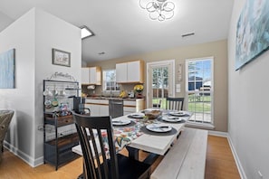 A modern kitchen with a dining area, a coffee station, and a view of the backyard.