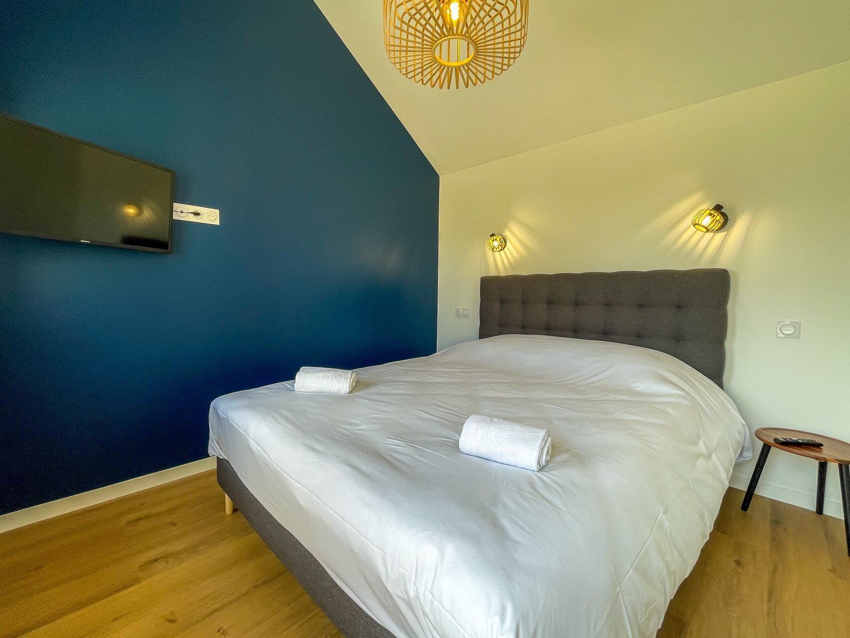 Ein Schlafzimmer mit einem großen Bett, einem flachbildfernseher an der Wand und zwei Wandleuchten.