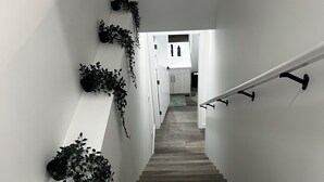 A wooden staircase with white walls, black handrails, and potted plants on the walls. - A feel of home in Fort Garry (Winnipeg)