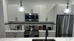A modern kitchen with stainless steel appliances, a marble countertop, and pendant lighting. - A feel of home in Fort Garry (Winnipeg)