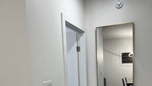 A hallway with a white door, a large mirror, and a dining area visible in the reflection. - A feel of home in Fort Garry (Winnipeg)