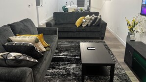 A modern living room with two grey sofas, a black coffee table, and a black rug. - A feel of home in Fort Garry (Winnipeg)