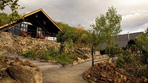A modern building with a stone facade and a wooden deck leading to a glass entrance.