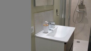 A bathroom with a white sink, a mirror, and a shower.