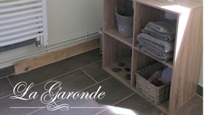 A small, neatly organized bathroom with a towel rack, a shelf with folded towels, and a basket. - Quiet Chambre des Daims (BERTHEN)