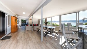 A spacious living area with a large window, a dining table, and a view of the outdoors.