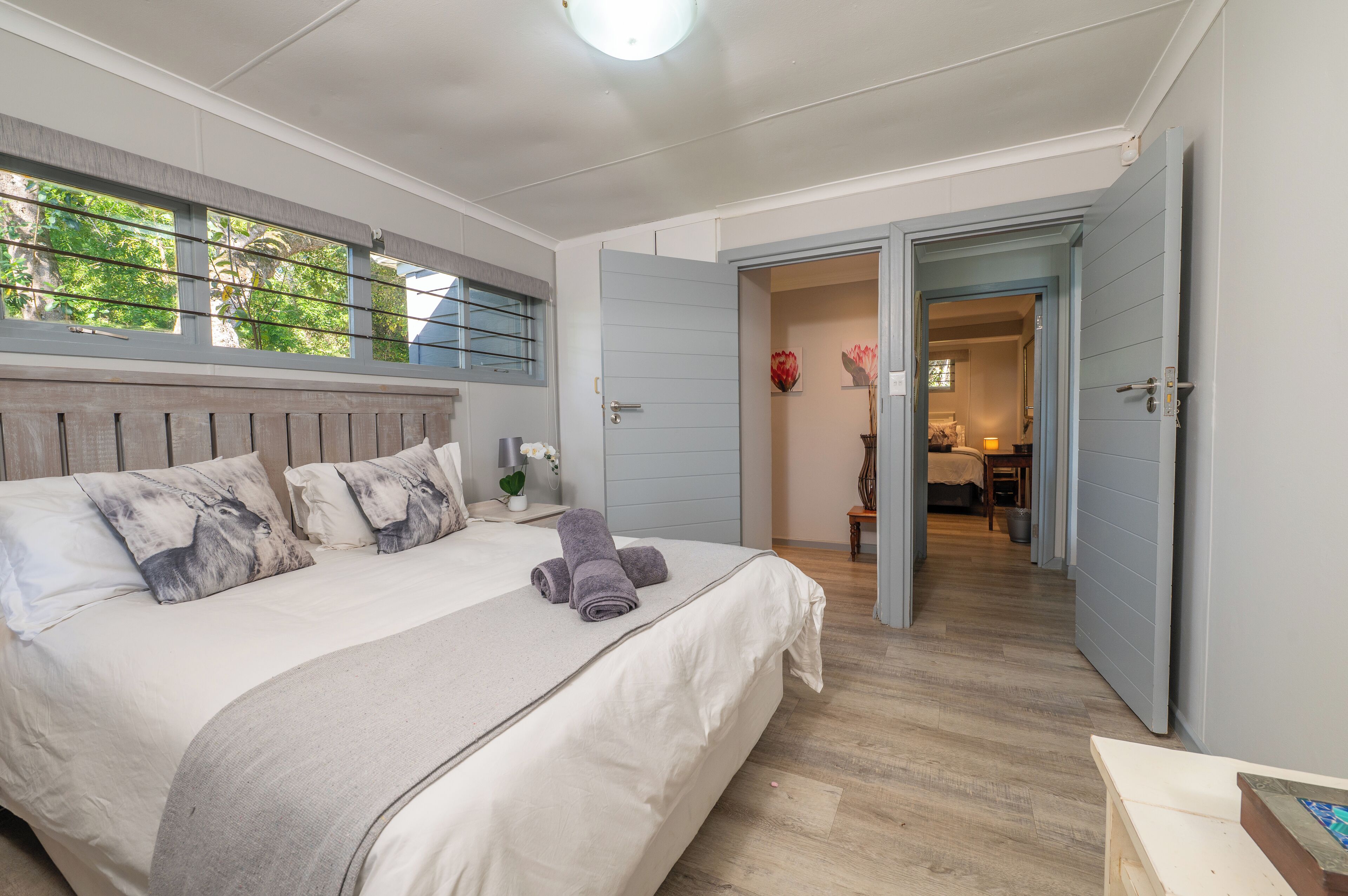 A bedroom with a large bed, a view of the hallway, and a door leading to another room.