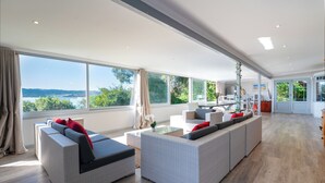 A spacious living area with large windows, wicker sofas, and a view of the outdoors.
