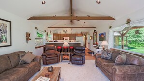 A spacious living room with leather sofas, a wooden coffee table, and a kitchen in the background.