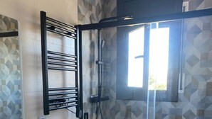 A modern bathroom with a glass-enclosed shower, a white sink, and a toilet. - Bright apartment with sea view (Calafell)