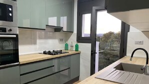 A modern kitchen with a built-in oven, a gas stove, and a sink. - Bright apartment with sea view (Calafell)