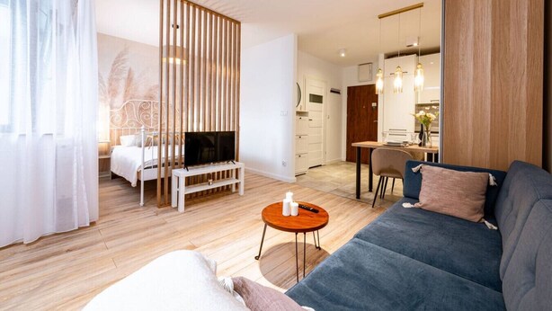 A modern living room with a sofa, TV, and a dining area.