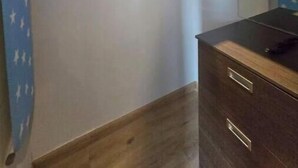 Una habitación pequeña con un aparador de madera, un espejo y una cortina azul con motivos de estrellas.
