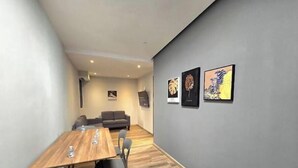 Una sala de reuniones moderna con una mesa de madera, paredes grises y obras de arte.