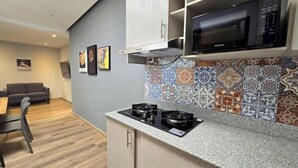 Una cocina compacta con estufa a gas, microondas y salpicadero de azulejos.