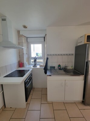 A compact kitchen with a stove, sink, and a window. - House for 2 to 4 people close to all amenities and 25 minutes from the sea (Mareuil-sur-Lay-Dissais)