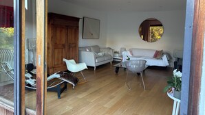 A modern living room with a wooden floor, two sofas, a glass coffee table, and a large mirror.