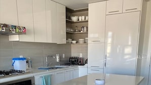 Eine moderne Küche mit einer zentralen Kochinsel, Edelstahlgeräten und Barhocker.