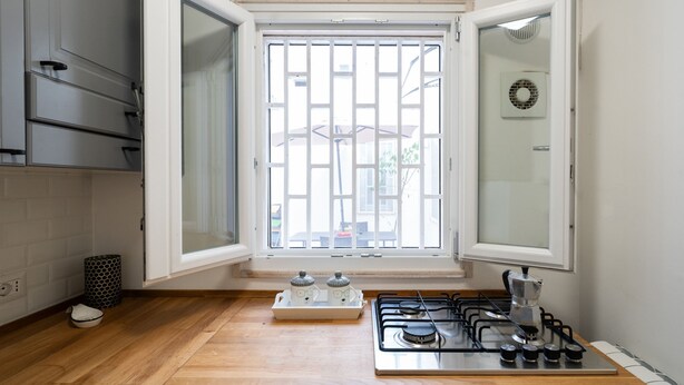 A kitchen with a gas stove, a window with bars, and a view of the outside. - Secret House by Wonderful Italy (Bari)