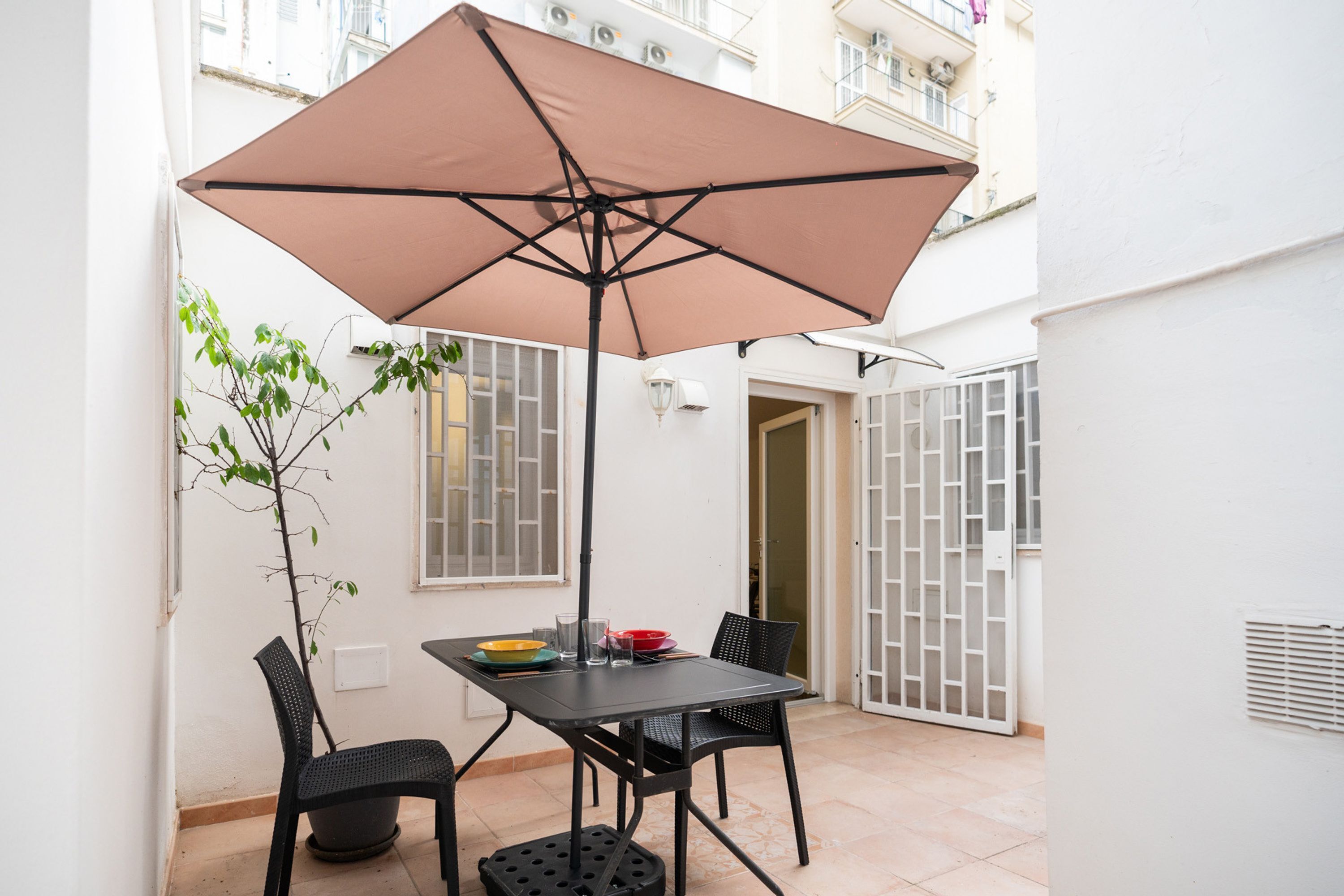 A patio with a table, chairs, a table umbrella, and a potted plant.