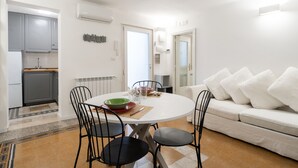 A modern kitchen with white cabinets, a dining table with four chairs, and a white sofa with cushions. - Secret House by Wonderful Italy (Bari)