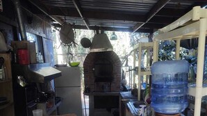 A rustic kitchen with a brick oven, a water dispenser, and a large water jug. - HOUSE OF ANCESTRAL MEDICINES AND MASTER PLANTS (tijuana)